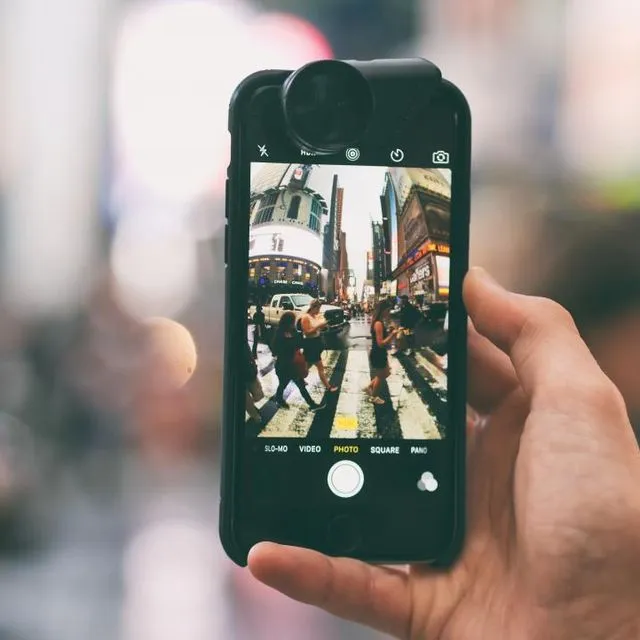 Un téléphone tenu en ville, écran allumé
