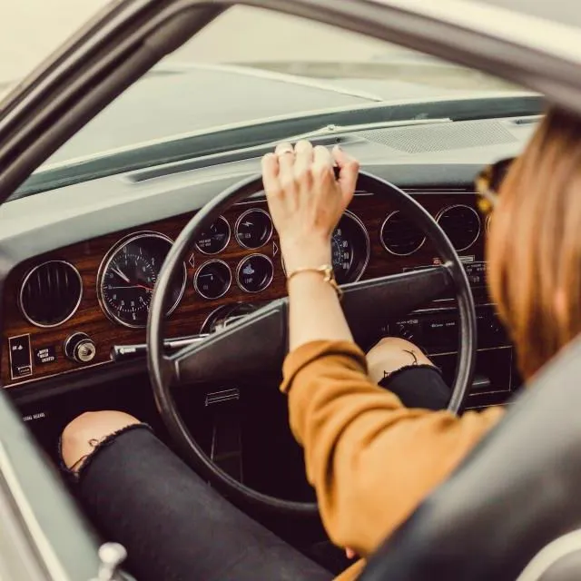 Une conductrice au volant, dans la lumière chaude de fin de journée