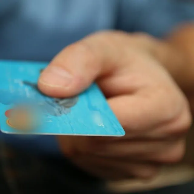 Une main tend une carte bancaire pour régler